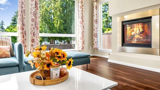 Una sala de estar con chimenea, un sofá y una mesa de centro con un jarrón de flores.