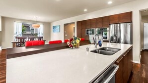 Una cocina moderna con una isla grande, electrodomésticos de acero inoxidable y armarios de madera.