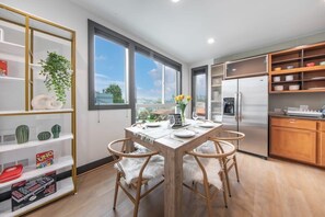 A modern kitchen with a dining table, chairs, and a large window.