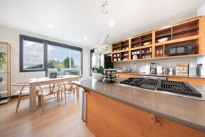 A modern kitchen with wooden cabinetry, a central island, and a dining area with a table and chairs.