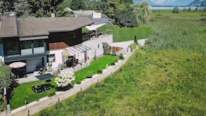 Uma casa moderna de dois andares com um jardim bem cuidado e vista para um lago.