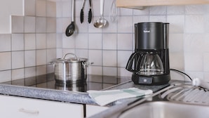 Uma cozinha com cafeteira, panela e utensílios sobre o balcão.