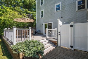 A residential deck with a white railing, a wooden staircase, and a potted plant.
