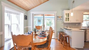 A dining area with a wooden table, chairs, and a view of the outdoors. - Private Pool, Large Deck, and Game Room! (Dennis)
