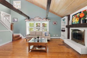 A living room with a fireplace, a sofa, a coffee table, and a staircase.