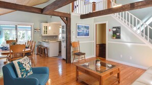 A spacious living area with wooden beams, a staircase, and a dining area with wooden chairs and a table. - Private Pool, Large Deck, and Game Room! (Dennis)