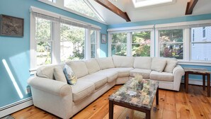 A living room with a beige sectional sofa, a wooden coffee table, and large windows with white frames. - Private Pool, Large Deck, and Game Room! (Dennis)