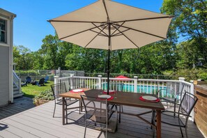 A deck with a table and chairs, a pool, and a white fence. - Private Pool, Large Deck, and Game Room! (Dennis)