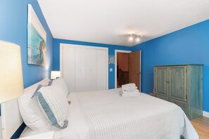 A bedroom with a bed, a wardrobe, and a door leading to another room. - Private Pool, Large Deck, and Game Room! (Dennis)