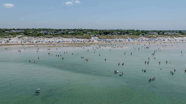 A beach with clear water, people swimming, and beach umbrellas. - Private Pool, Large Deck, and Game Room! (Dennis)