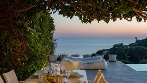 An outdoor dining area with a table set for a meal, overlooking the sea. - New property_Sa Turri: Relax, Infinity Pool, Seaview, enchanting Sunsets (Torre Delle Stelle (Maracalagonis))