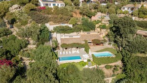 An aerial view of a residential area with a swimming pool, multiple houses, and lush greenery. - New property_Sa Turri: Relax, Infinity Pool, Seaview, enchanting Sunsets (Torre Delle Stelle (Maracalagonis))