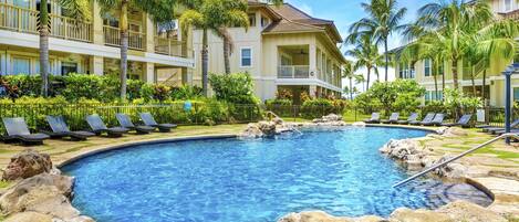 A resort with a swimming pool surrounded by palm trees and lounge chairs.