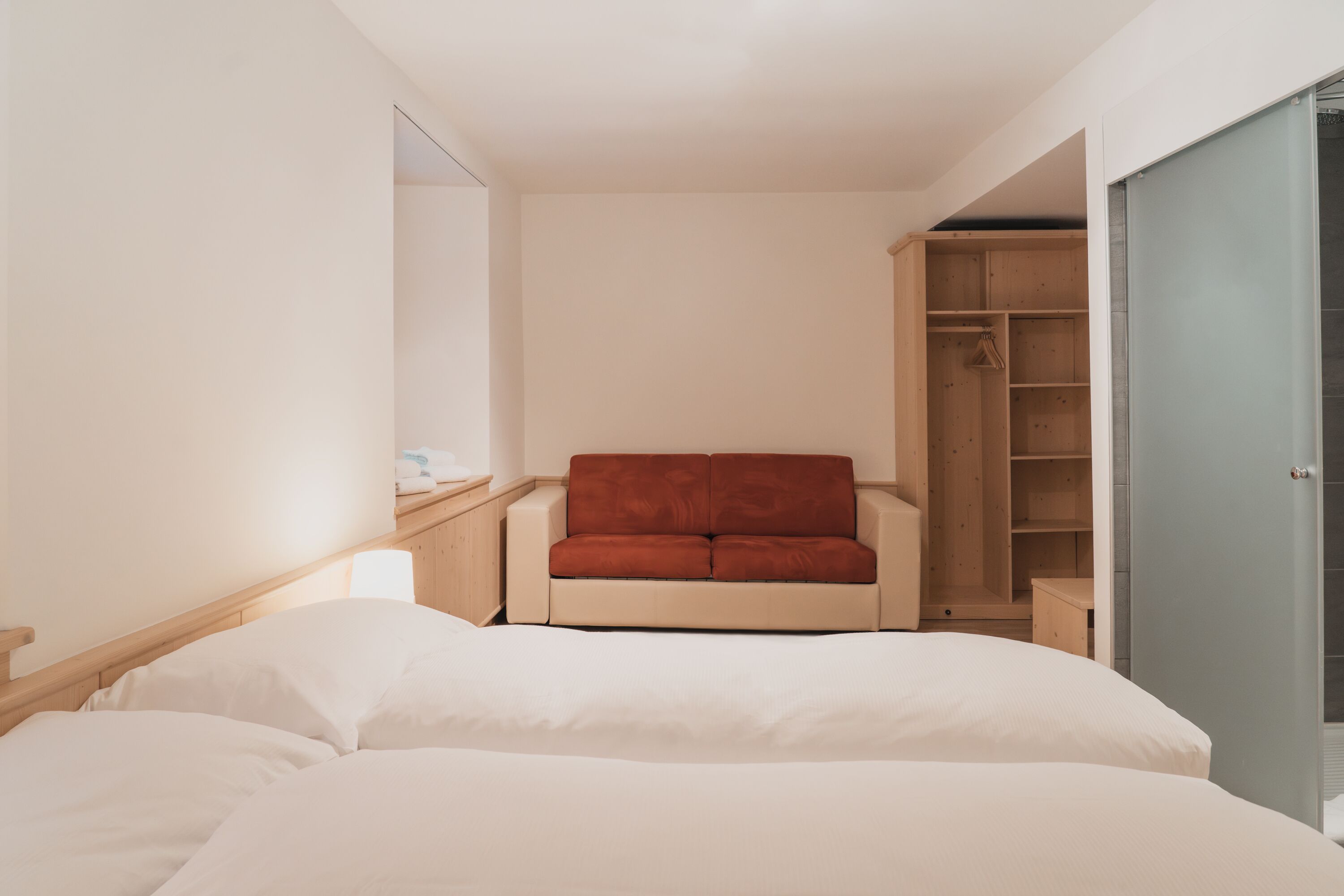 Ein Hotelzimmer mit einem Bett, einem roten Sofa, einem Holzschrank und einem Spiegel.
