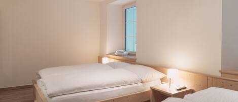 Ein Schlafzimmer mit einem hölzernen Bett, einem Nachttisch, einer Lampe und einem Fenster.