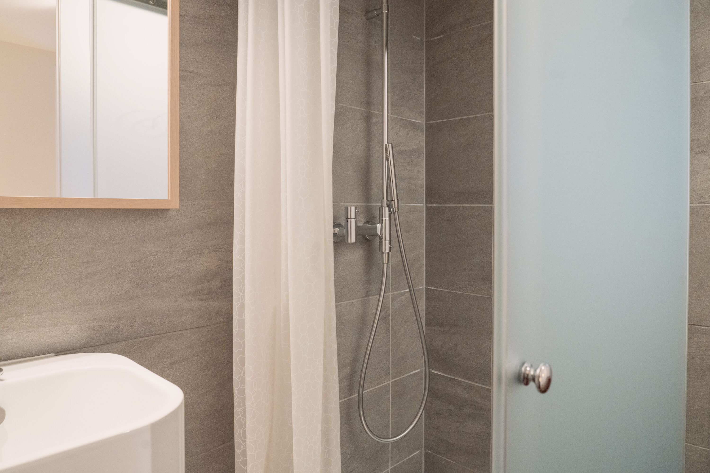 A bathroom with a shower, a sink, and a mirror.