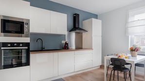 Una cocina moderna con armarios blancos, un microondas negro, un horno de acero inoxidable y una campana extractora negra.