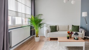 Una sala de estar moderna con un sofá blanco, una mesa de centro, una planta en maceta y una lámpara de pie.