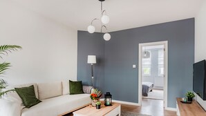 Una sala de estar moderna con un sofá, una mesa de centro y un televisor sobre un mueble de madera.