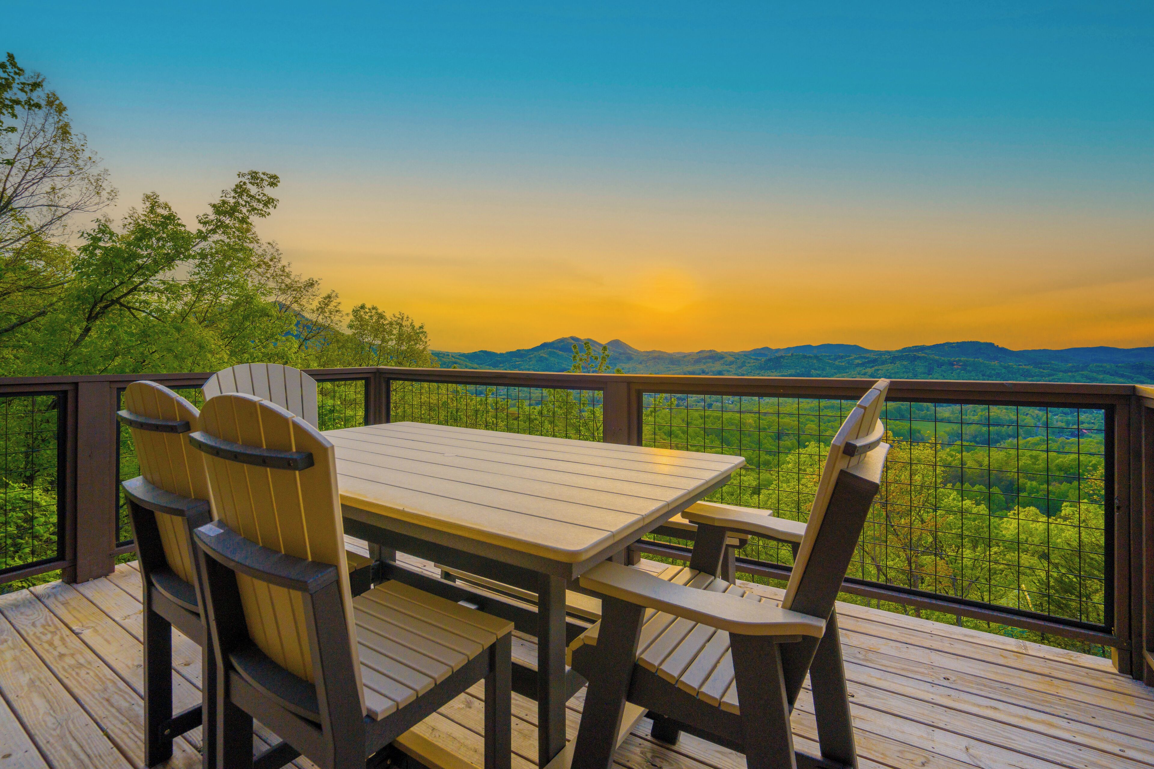 A wooden deck with a table and chairs, overlooking a mountainous landscape.