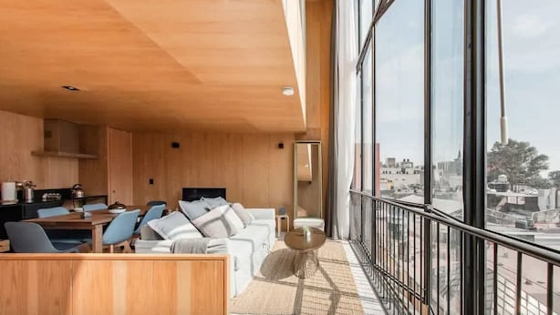 Un intérieur moderne comprenant un coin repas, un canapé et de grandes fenêtres donnant sur la ville.