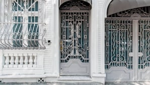Un bâtiment blanc, doté de grilles en métal ouvragées et d’une fenêtre ornée de barreaux décoratifs.