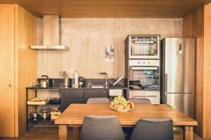 A compact kitchen with a wooden table, a refrigerator, and a built-in oven.