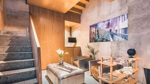 A modern interior with a staircase, a seating area with a cushioned bench, a wooden side table, and a wall-mounted shelf with books and a globe. - Eco Loft with Terrace Garden & Gym Access (Ciudad de México)