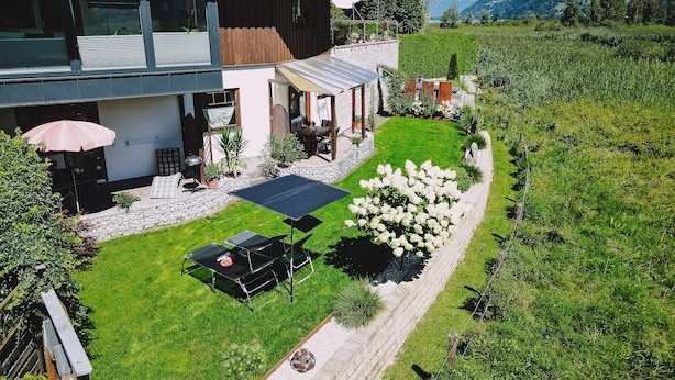 A modern house with a patio, a dining area, and a garden. - Appartement Plattner - TOP 2 (Zell am See)