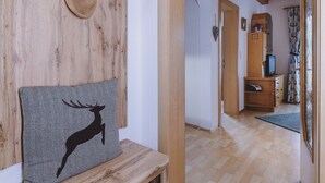 A wooden wall with a woven basket and a framed deer picture. A wooden bench is in the foreground. - Appartement Plattner - TOP 2 (Zell am See)