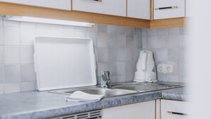 A modern kitchen with white cabinets, a granite countertop, a built-in oven, and a coffee maker. - Appartement Plattner - TOP 2 (Zell am See)