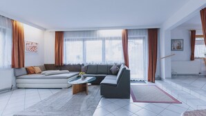 A modern living room with a grey sectional sofa, a coffee table, and a rug. - Appartement Plattner - TOP 3 (Zell am See)