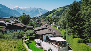 A modern house with a stone facade, a covered patio, and a view of mountains. - Appartement Plattner - TOP 3 (Zell am See)