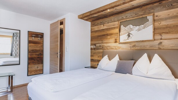 Een slaapkamer met een groot bed, houten wandpanelen, een ingelijst kunstwerk en een deur.