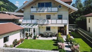 Een gebouw met twee verdiepingen, een balkon, een overdekt terras en een verzorgd gazon.
