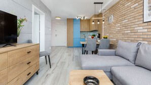 A modern living room with a grey sofa, wooden coffee table, and a TV on a wooden cabinet. - Seaside Apartamenty Platany Kołobrzeg  (Kolobrzeg)
