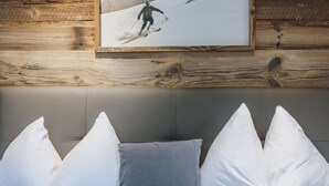A bed with white and gray pillows, a framed picture of a skier on the wall, and wooden paneling. - Appartement Haus Elise - TOP 3, balcony & mountain view (Zell am See)