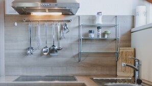 A modern kitchen with stainless steel appliances, a hanging utensil rack, and a wooden backsplash. - Appartement Haus Elise - TOP 3, balcony & mountain view (Zell am See)