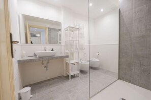 Ein modernes Badezimmer mit großem Spiegel, einem Aufsatzwaschbecken, einem Bidet und einer Duschkabine.