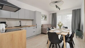 Una cocina moderna con gabinetes grises, una isla de madera y un comedor con mesa lista para cuatro.