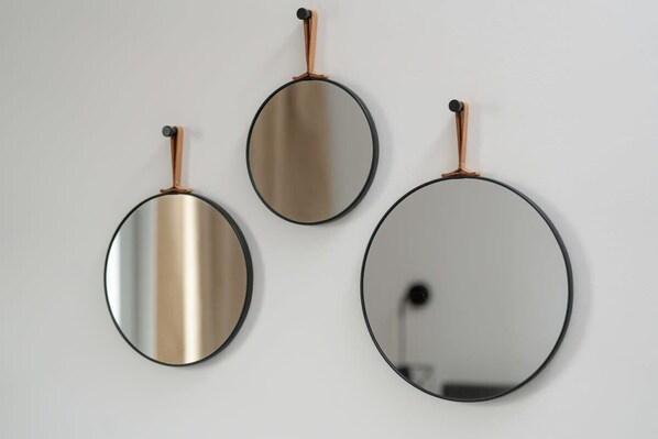Trois miroirs ronds, dotés de cadres en cuivre, sont accrochés à un mur uni.