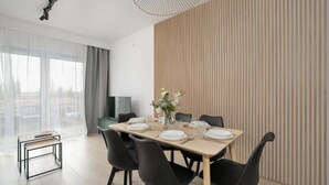 Un comedor moderno con una mesa de madera preparada para cuatro personas, sillas negras y un florero con flores.