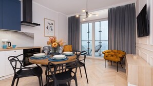 A modern kitchen with a dining area, a large window with curtains, and a view of the city. - Stylish Apartment in Wola | Balcony and Air Conditioning (Warszawa)