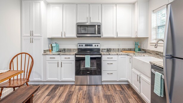 A modern kitchen with white cabinets, a stainless steel refrigerator, a built-in oven, and a microwave. - 3BR Home | Near Savannah and Marina + Workspace (Savannah)