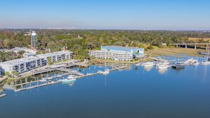 An aerial view of a marina with boats docked, a large building with multiple floors, and surrounding greenery. - 3BR Home | Near Savannah and Marina + Workspace (Savannah)