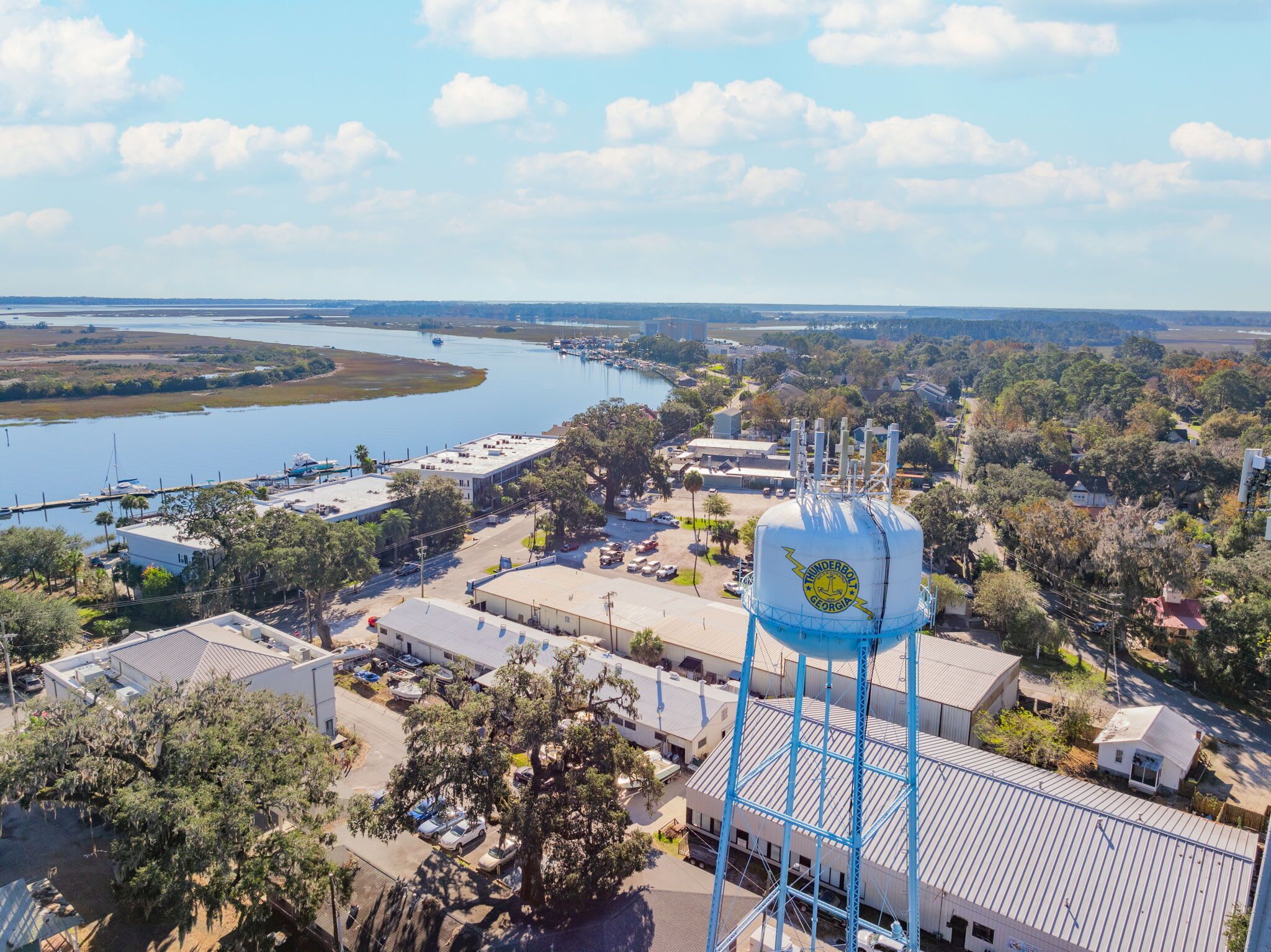 A water tower with a blue structure and a logo, surrounded by buildings and a marina with boats.