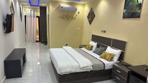 Una habitación de hotel moderna con una cama grande, mesitas de noche, un aparador y un televisor.
