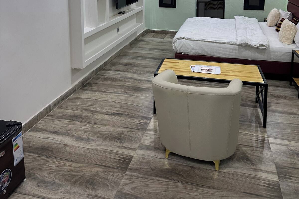 A modern hotel room with a bed, a sofa, a TV mounted on the wall, and a wooden coffee table.