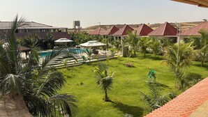 Un resort con piscina, palmeras y edificios de techos rojos.