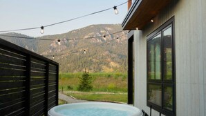 Ein Whirlpool mit Blick auf die Berge, eine Holzlattenveranda und Lichterketten.